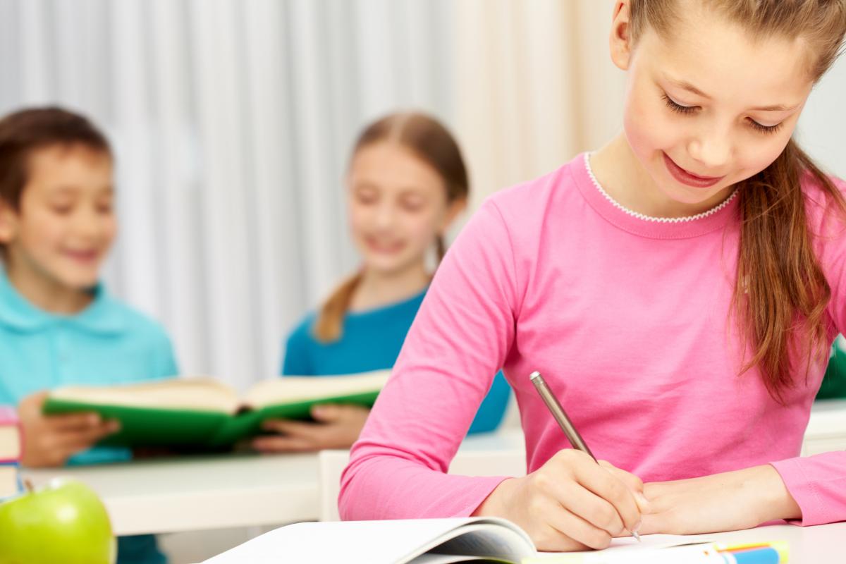 young girl writing and smiling.