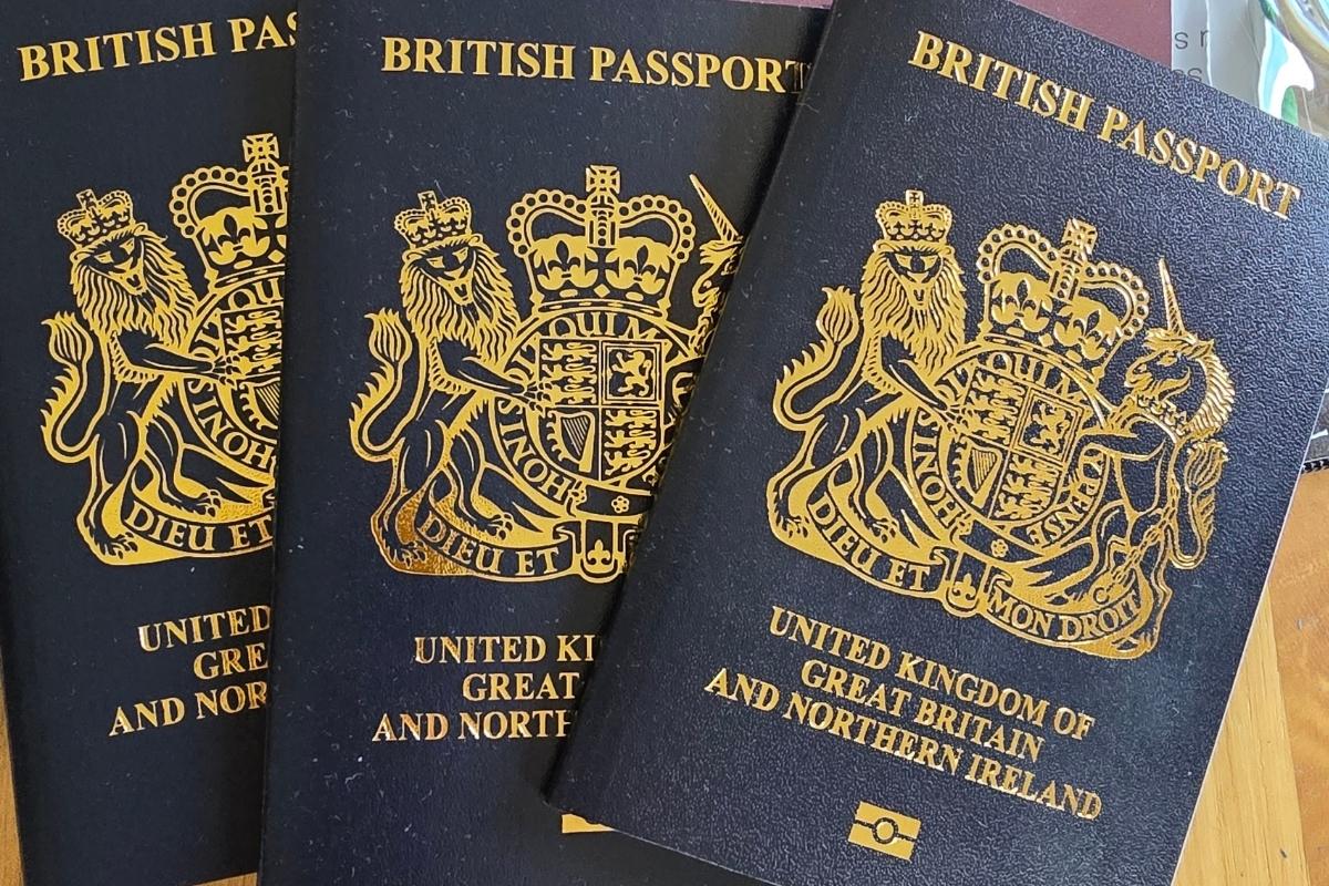 Three British passports with dark blue covers and gold crest reading "United Kingdom of Great Britain and Northern Ireland" are placed side by side on a surface.
